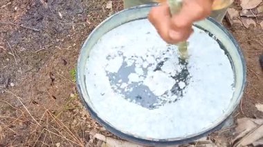 Bir çiftçi gün boyunca bahçede sıvı gübre karışımı karıştırıyor.