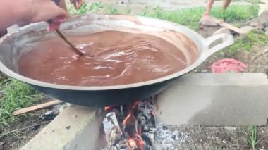 Gün boyunca sıcak çikolatalı pudingi ateşle karıştıran bir kadının elleri.