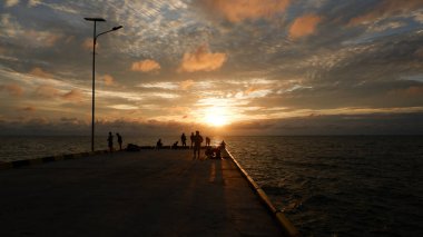 Tanjung Yılan Güneşi, Endonezya 'da İnsanların Silüetleri Altında Doğal Gün Batımı Işınları
