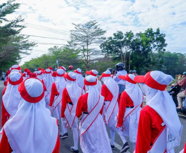 MUNTOK, İNDONEZYA - 10 Eylül 2023: Kırmızı ve beyaz kostümlü orta okul öğrencilerinin yürüyüşüne katılan takımlar
