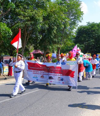 MUNTOK, INDONEZYA - 10 Eylül 2023: Öğrenci Karnaval katılımcıları Endonezya Cumhuriyeti 'nin yıldönümü anısına bayraklar ve pankartlar taşıyor