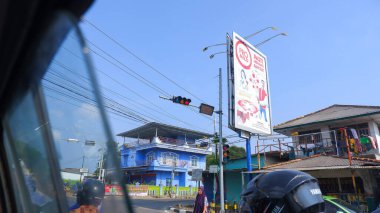 PANGKALPINANG, İNDONEZYA - 12 Ekim 2023: Şehir Yolunda Reklam panosu olan bir ev, Araba Pencere çerçevesinden alınan fotoğraf