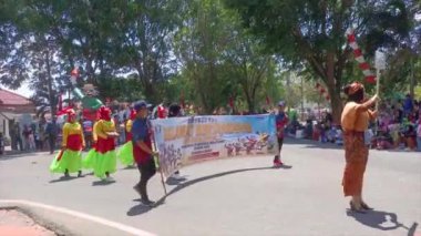 MUNTOK, Indonezya - 15 Eylül 2023: Renkli Yerel Dansçı kostümleri içindeki bir grup Karnaval katılımcısının eşleşmesi, Endonezya 'nın Bağımsızlık Günü boyunca