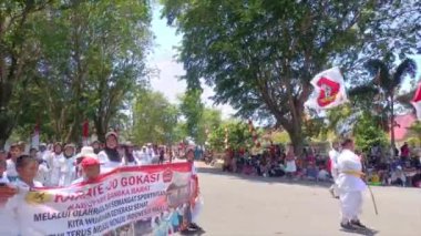 MUNTOK, INDONEZYA - 15 Eylül 2023: Endonezya Bağımsızlık Günü Kutlaması sırasında Beyaz Kostümler Giyen Bir grup Çocuk Silat Sporcusu Karnaval katılımcısı