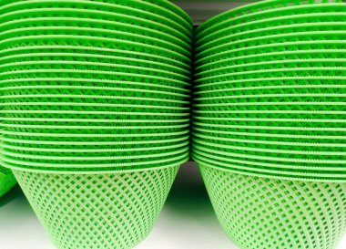 Yeşil plastik vazolardan yapılmış, düzgünce yerleştirilmiş ve bir rafta sıkıca duran meyve vazoları.