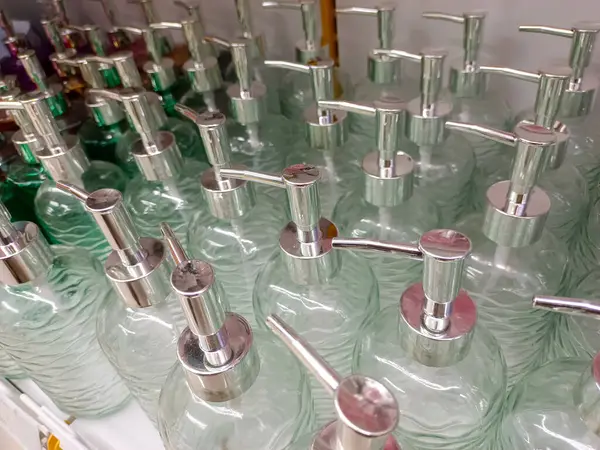 Şampuan ya da sabun kapları gibi temiz cam şişeler düzgün ve minimarket bir rafta sergilenir.