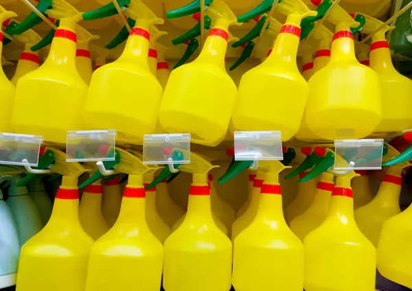 Sarı plastik sprey şişe koleksiyonu düzgünce asılmış ve mobilya dükkanında sergilenmiş.