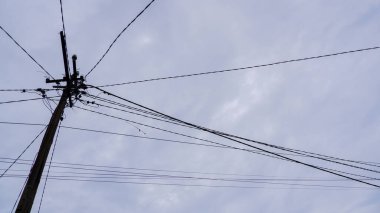 Elektrik direğinin silüeti ve gri bir gökyüzüne karşı kablo