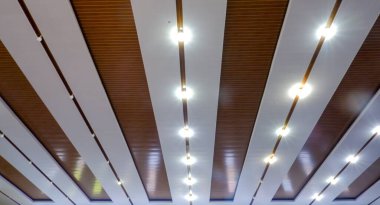 Beyaz ve kahverengi renk desenleri ve aydınlatılmış ışıkları olan çok amaçlı bir bina ya da salon