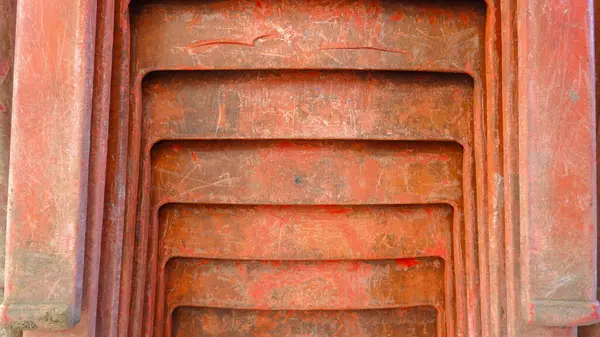 Turuncu plastik sandalyenin ön tarafının görüntüsü düzgün ve sıkıca yerleştirilmiş, portre modunda çekilmiş.