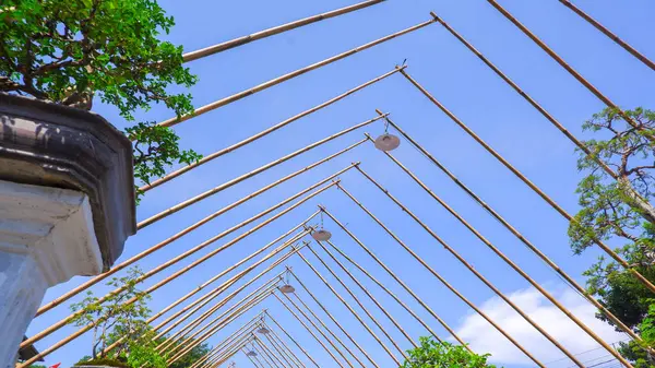 Bambu çatı iskeletinin altından birkaç asılı ışık ve mavi gökyüzü manzaralı bir manzara.
