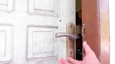 Yüzeyinde güneş ışığı olan bir adamın eli kapı kolunu çevirir ve kapıyı kapatır.