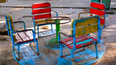 Dört renkli ahşap koltuklu ve metal direksiyonlu yıpranmış eski bir atlıkarınca. Boya soyuluyor ve soluyor, oyuna eski ve nostaljik bir görünüm katıyor.