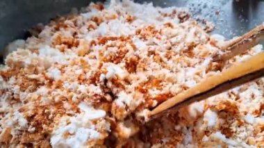 Urap için baharat karışımını karıştırma sürecinin 4K görüntüsü, tipik bir Endonezya yemeği, yavaş yavaş büyük bir konteynırda karıştırılıyor.