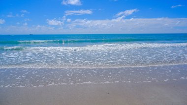 Sahil manzaralı sakin dalgalar sahile çarpıyor, barışçıl ve davetkar bir atmosfer sunuyor.