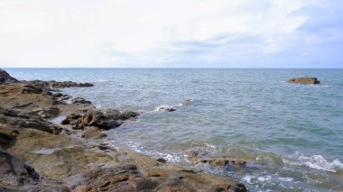 Uçsuz bucaksız okyanusla karşılaşan kayalık bir kıyı şeridinin büyüleyici doğal manzarası. Dik kayalıklar, desenli yüzeyler ve değişen yüksekliklerle çerçevenin sol tarafına hükmediyor..