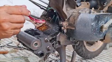 Motor parçalarını temizlerken ya da motosikletin şanzıman alanlarını temizlerken yakın çekim. Bileşenler metalden yapılmış ve aşınma ve kir izleri var..