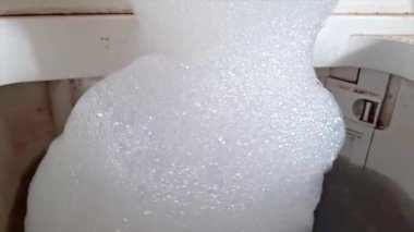 Çamaşır makinesinin içindeki kalın, ince bir sabun köpüğü yığınına yakın çekim..