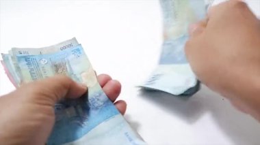 50 bin rupia banknot sayan bir çift elin beyaz arka planda izole edilmiş görüntüleri.