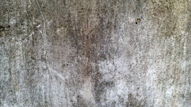 Yıpranmış ve desenli beton ya da çimento yüzeyinin detaylı bir yakın çekimi. Renk paleti, tonu değişen, yaşı ve maruziyeti belirten sessiz griler tarafından yönetilir..
