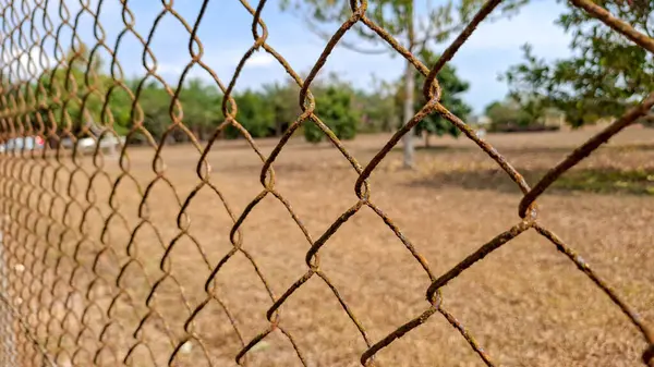 Yıpranmış ve paslı dikenli tellerin yakın plan çekimi. Ön planda, oksitlenme belirtileri gösteren eski metaller var..