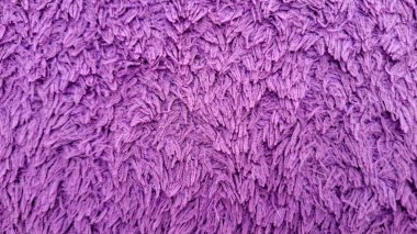 Yumuşak mor kumaş dokusunun detaylı bir yakın çekimi, belki bir havlu, halı ya da mikrofiber kumaştan..