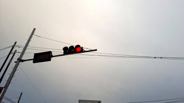 Bulutlu, bulutlu bir gökyüzünde kırmızı bir trafik ışığı asılı.