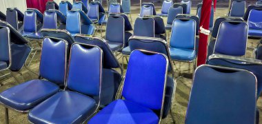 Görüntü, kapalı bir etkinlik veya halka açık bir toplantı için düzenlenmiş, krom çerçeveli birkaç sıra mavi vinil sandalyeleri gösteriyor.