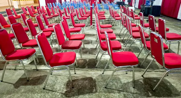 Kırmızı yastıklı sandalyelerin geniş açı görünümü, kapalı bir etkinlikte ya da seminer salonunda mükemmel bir şekilde sıralanmış sıralanmıştır.