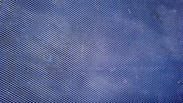 Detaylı geometrik ızgara desenli mavi tel örgü dokusuna yakın çekim. Elmas şekilli delikler güçlü bir endüstriyel ve modern estetik yaratır..