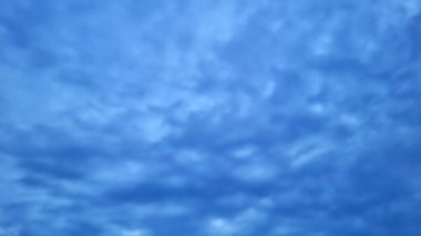 Alacakaranlıkta dramatik bulutlu mavi gökyüzü soyut arkaplanı. Yumuşak bulut oluşumları gökyüzüne yayılarak barışçıl ama kasvetli bir atmosfer yaratıyor..