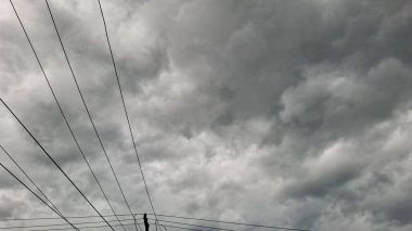 Bulutlu, fırtınalı bir gökyüzünün yukarıdaki elektrik hatlarıyla noktalanmış anlamlı bir görüntüsü. Dramatik bulut desenine göre yaklaşan bir fırtına gerginlik ve atmosfer hissi yaratıyor..