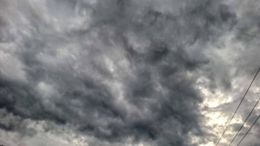 Kasvetli fırtına bulutlarının çarpıcı görüntüsü girdap ve katmanlar halinde korkunç bir hava sahnesi oluşturuyor. Yoğun gri fırtına bulutlarıyla dolu dramatik bir gökyüzü.