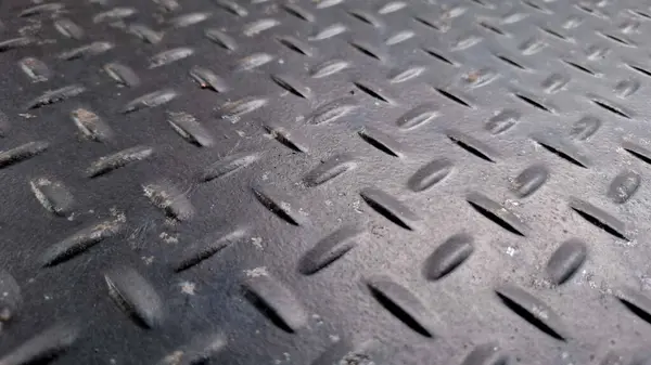 Karanlık desenli elmas metal yüzeyin mesafeye kadar uzanan dinamik düşük açılı perspektif görüntüsü..