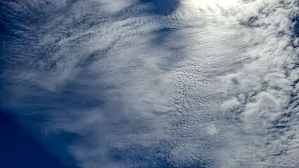 A sweeping view of the sky with a stunning expanse of altocumulus clouds. The clouds display a variety of formations, from rippling and wavy patterns to more scattered, textured patches.