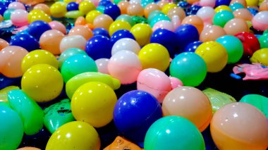 Suyun üzerinde yüzen renkli plastik toplardan oluşan geniş bir koleksiyonun yer aldığı geniş açılı bir fotoğraf. Genellikle çocuk oyunlarında, top havuzlarında ya da lunaparklarda bulunur..