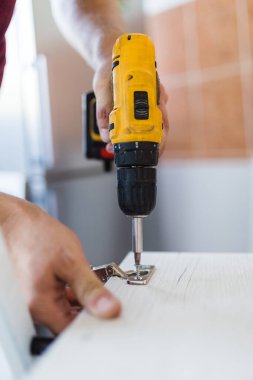 Elinde kablosuz tornavida tutan adamı kapat ve evde mobilya montajı yaparken vida vidaları yalan söylüyor.