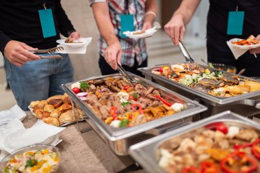 People choosing fresh prepared food from buffet table.
