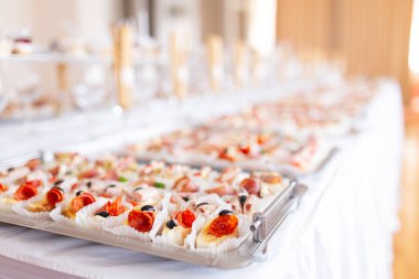 Açık büfe masada plaka servis edilen çeşitli kanepeler yakın.