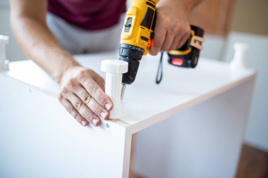 Man installing new furniture at his home and using cordless screwdriver