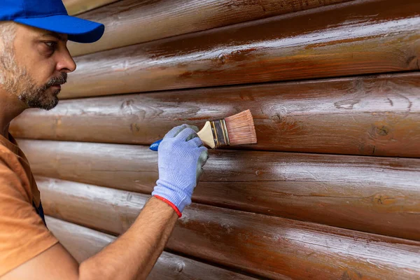 Worker Applying Stain Brush Wooden House Exterior Wall Royaltyfria Stockfoton