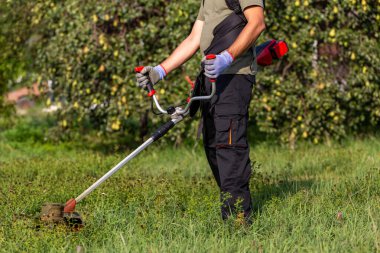 Gardening concept. Man cutting the lawn with electric grass trimmer.