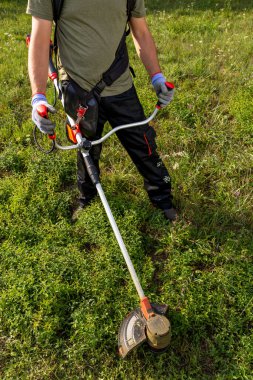 High angle view of man mowing the grass at his garden by using string trimmer