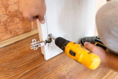 Elinde kablosuz tornavida tutan adamı kapat ve evde mobilya montajı yaparken vida vidaları yalan söylüyor.