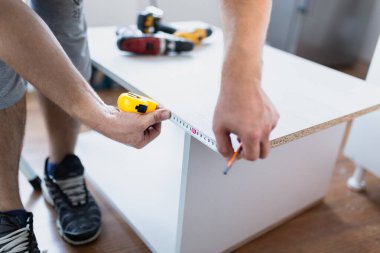 Tamirci mutfak malzemeleri yerleştirirken mezura kullanıyor. Ev onarımı kavramı.