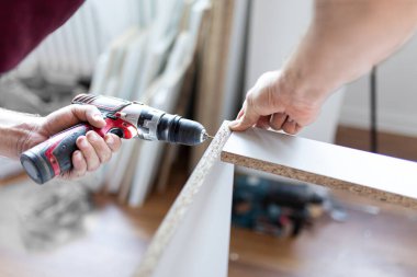 Erkek işçi mutfak dolabını monte etmek için kendi kendine montaj kiti kullanıyor..