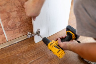 Sanatçı, kablosuz tornavida kullanarak mobilya monte ediyor. Mutfak Dolapları kurulum konsepti.