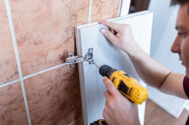 İçerde kablosuz tornavida kullanarak mobilya monte eden adam..