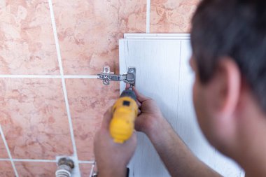 Elinde kablosuz tornavida tutan adam ve evde mobilya montajı yaparken vida vida vidaları yalan söylüyor.