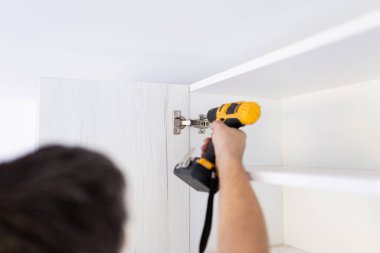 İşçi mutfak kapısını tornavida kullanarak kuruyor. Ev yenileme konsepti.